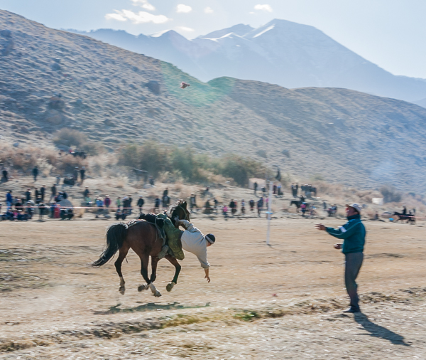 Kyrgyz rider picking up coins from the ground at the Barskoon