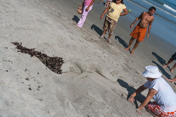 Lady sculpting sun-bather out of sand, Florida