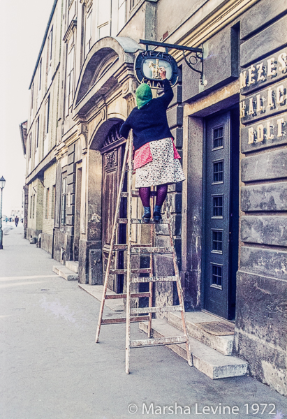 Lady painting a shop sign in Budapest (Hungary)