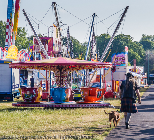 Man walking dog through fun fair, Cambridge